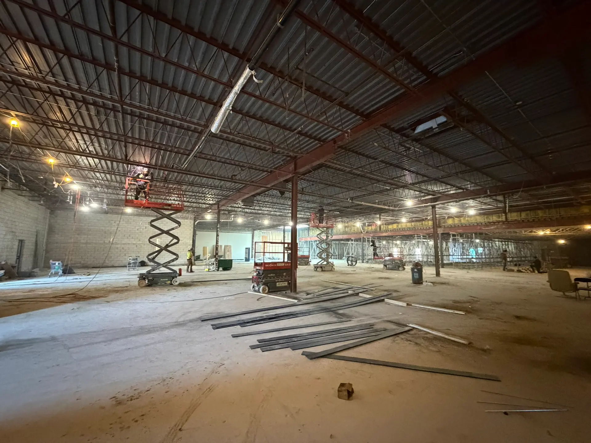 Wide view of a commercial jobsite with scissor lifts at work and shoring scaffold carrying the roof structure