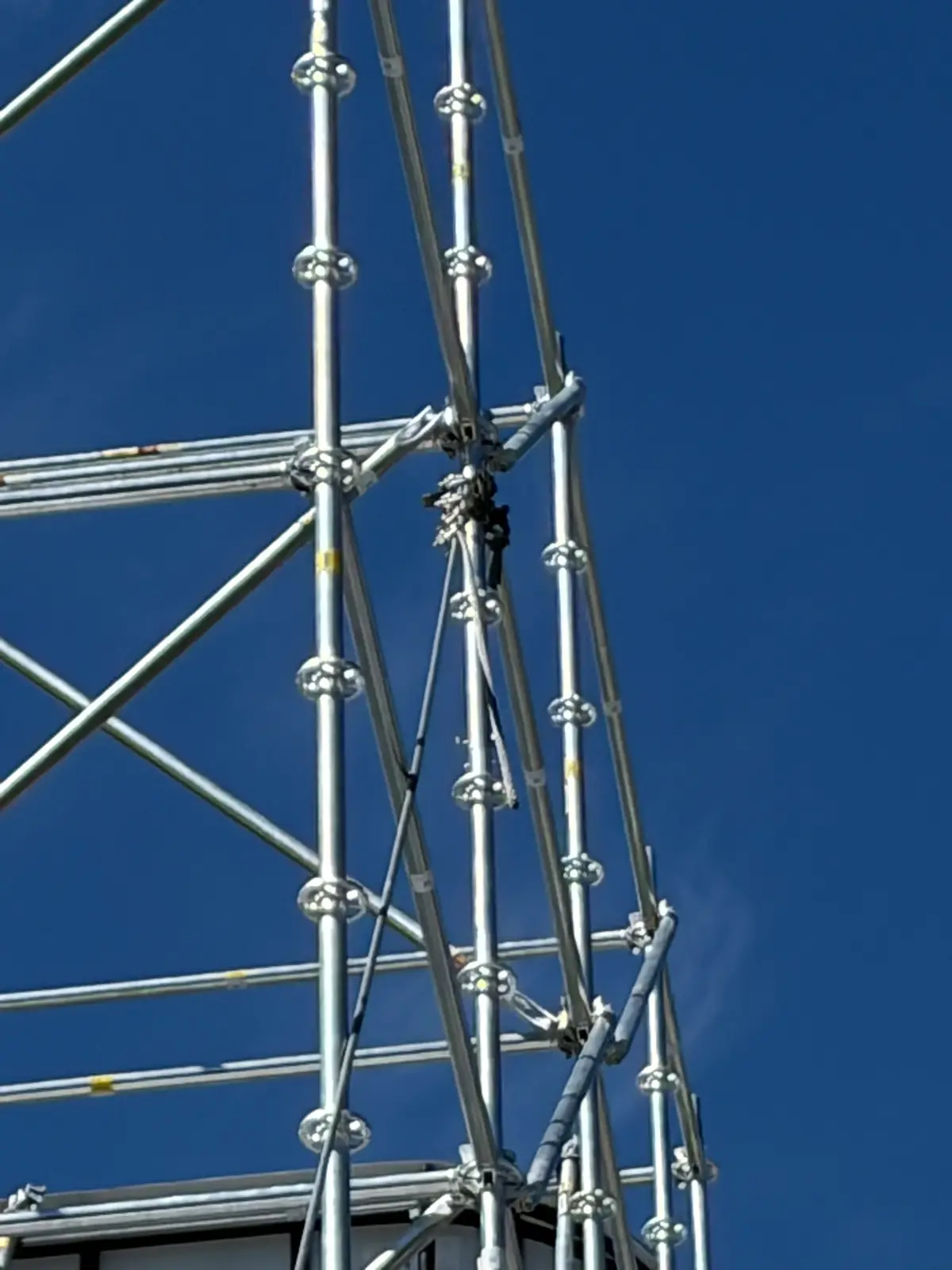 Ringlock scaffold standards, rosettes and diagonal braces rising against a deep blue sky