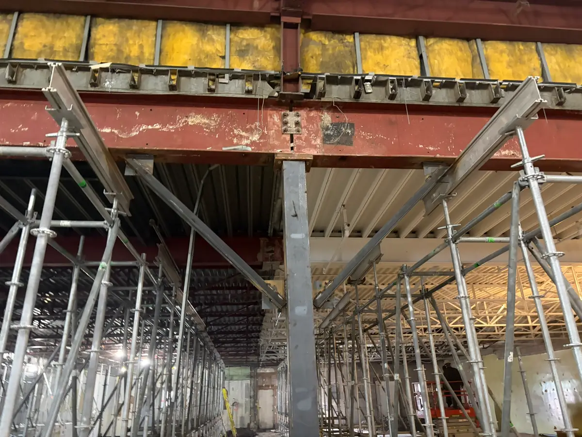 Symmetrical view of shoring towers flanking a steel column and transfer beam during interior structural renovations