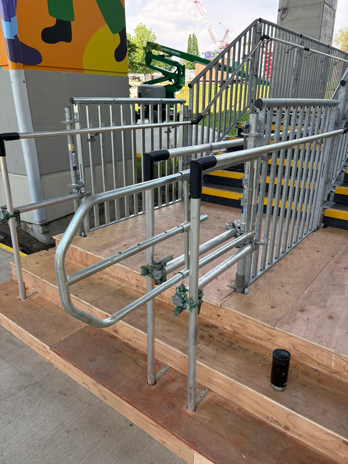 Galvanized temporary access stair with continuous handrails built over a plywood deck at an event site